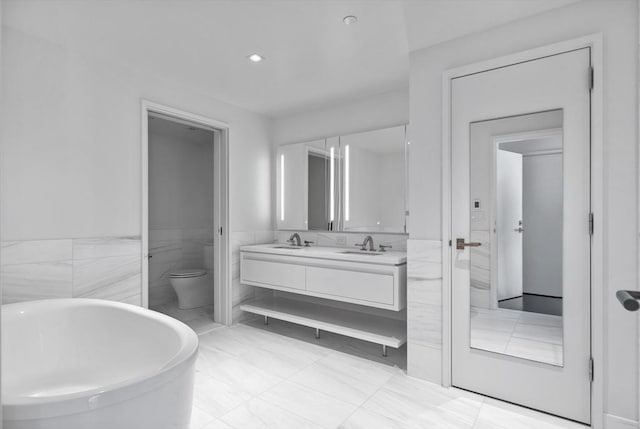 bathroom featuring vanity, tile walls, a bathtub, and toilet