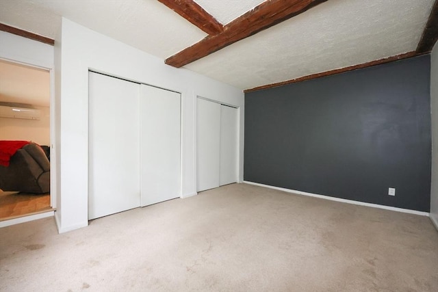 268 Wallace Hill Rd, Townsend, MA 01469 - unfurnished bedroom featuring multiple closets, carpet floors, baseboards, and beamed ceiling