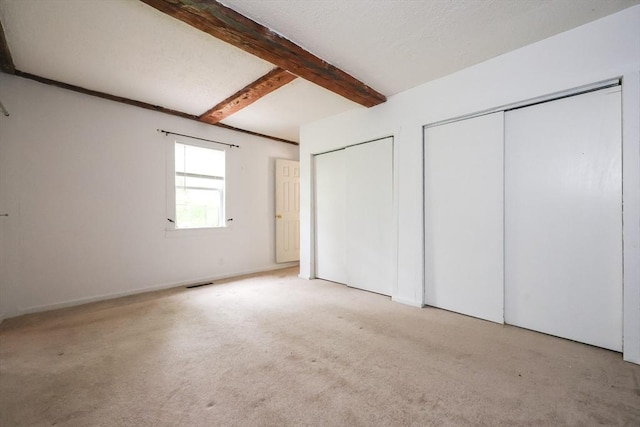 268 Wallace Hill Rd, Townsend, MA 01469 - unfurnished bedroom featuring two closets, beamed ceiling, carpet flooring, and baseboards
