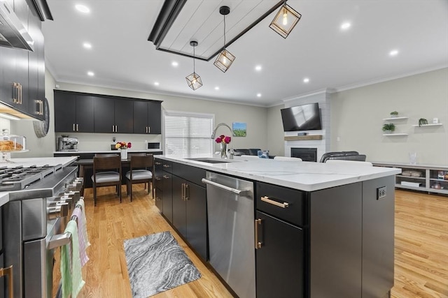 33 Peirce St Unit 1, Waltham, MA 02453 - kitchen with open floor plan, under cabinet range hood, dark cabinetry, appliances with stainless steel finishes, and a sink