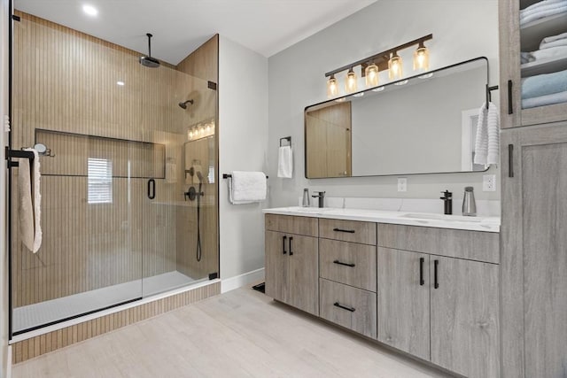 33 Peirce St Unit 1, Waltham, MA 02453 - bathroom featuring a shower stall, wood finished floors, a sink, double vanity, and baseboards