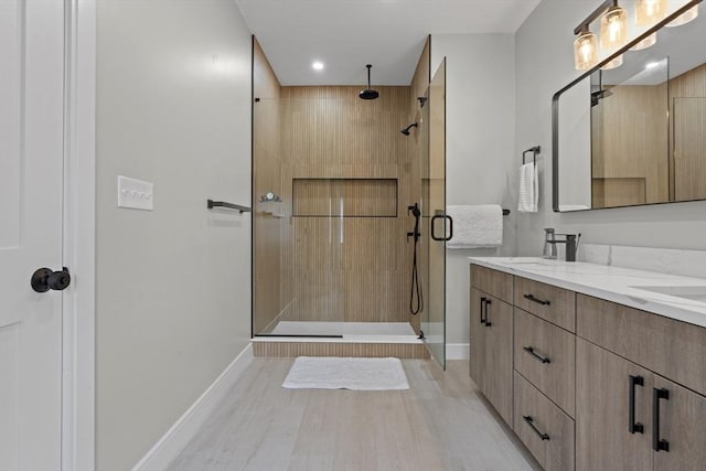 33 Peirce St Unit 1, Waltham, MA 02453 - bathroom with baseboards, a sink, double vanity, wood finished floors, and a stall shower