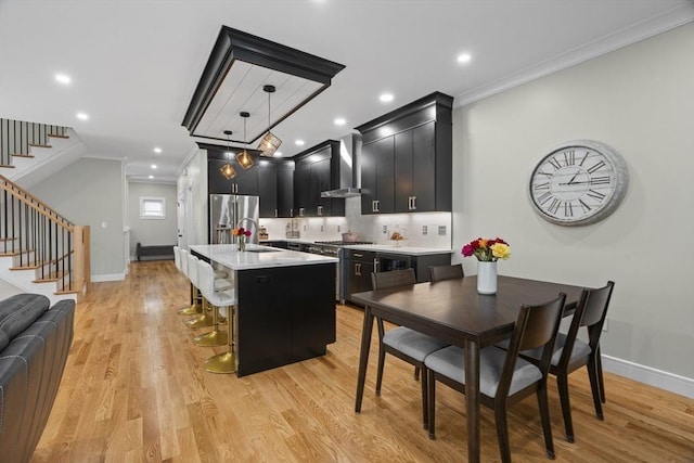 33 Peirce St Unit 1, Waltham, MA 02453 - kitchen featuring dark cabinets, wall chimney range hood, ornamental molding, appliances with stainless steel finishes, and light countertops