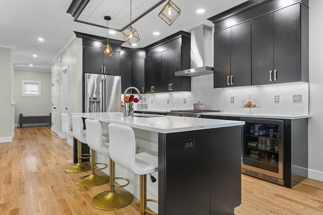 33 Peirce St Unit 1, Waltham, MA 02453 - kitchen featuring wall chimney exhaust hood, beverage cooler, stainless steel appliances, dark cabinetry, and backsplash