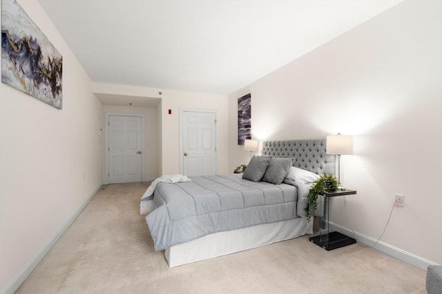 bedroom with light colored carpet and baseboards