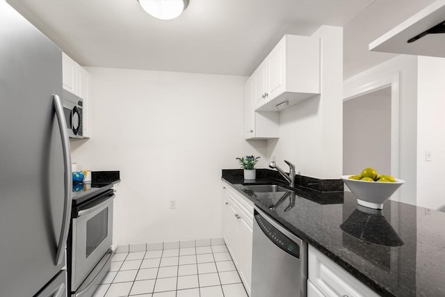 kitchen featuring appliances with stainless steel finishes, a sink, white cabinetry, and dark stone counters