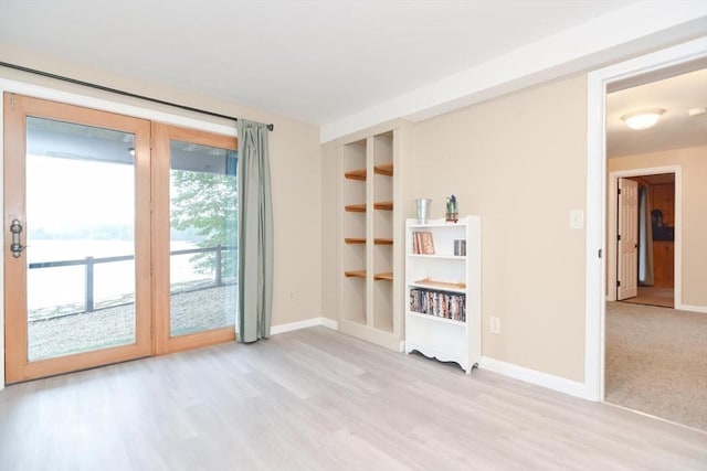 empty room with built in features and light hardwood / wood-style flooring