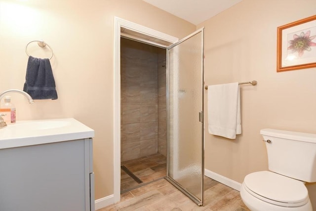 bathroom with hardwood / wood-style flooring, vanity, toilet, and a tile shower