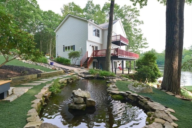 back of house featuring a balcony, a small pond, and a deck