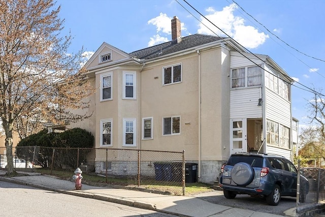 136-138 N St, Somerville, MA 02144 - view of home's exterior with fence private yard, stucco siding, and a chimney