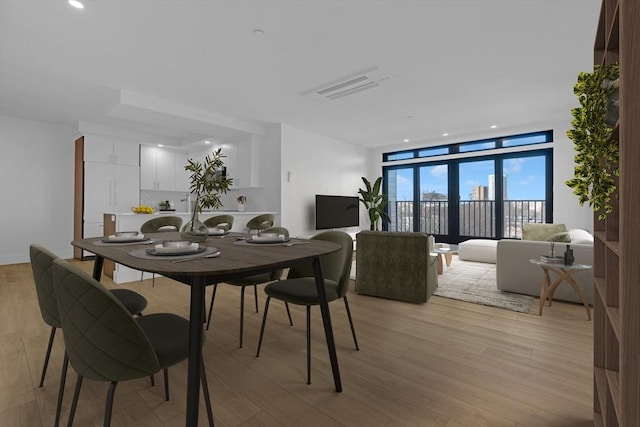 dining space with light wood-style floors, recessed lighting, visible vents, and a wall of windows