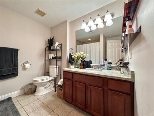 bathroom with toilet, vanity, and tile patterned flooring