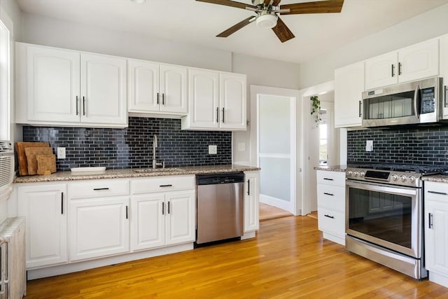 67 Jamaica Unit 3, Boston, MA 02130 - kitchen featuring stainless steel appliances, a sink, a ceiling fan, radiator heating unit, and backsplash