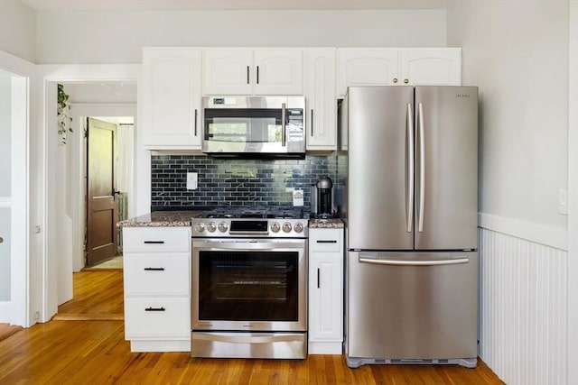 67 Jamaica Unit 3, Boston, MA 02130 - kitchen with stainless steel appliances, white cabinets, light wood-type flooring, dark stone countertops, and wainscoting