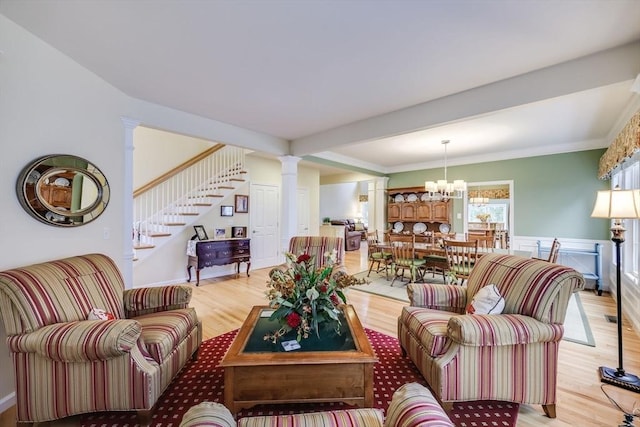 living room with a chandelier, light hardwood / wood-style floors, and decorative columns