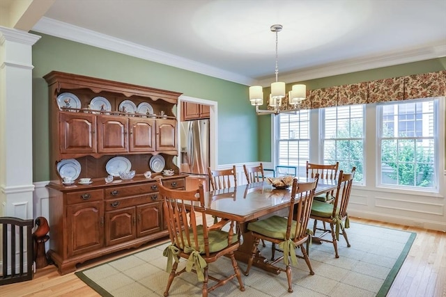 dining space featuring a notable chandelier, ornamental molding, and light wood-type flooring