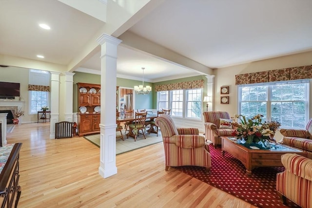 living room with a high end fireplace, light hardwood / wood-style flooring, decorative columns, and beamed ceiling