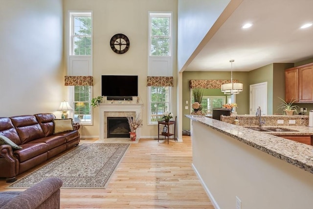 living room with a towering ceiling, sink, and light wood-type flooring