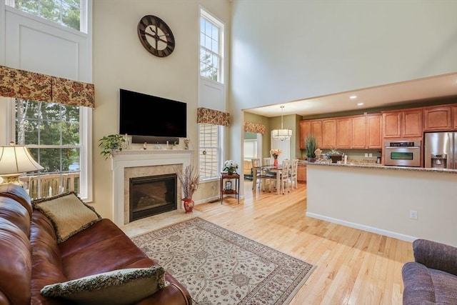 living room with a fireplace, a towering ceiling, a wealth of natural light, and light hardwood / wood-style floors