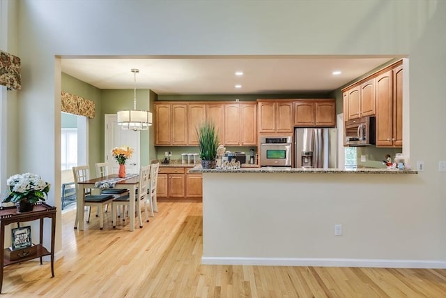 kitchen featuring decorative light fixtures, a chandelier, stainless steel appliances, light stone countertops, and light hardwood / wood-style floors