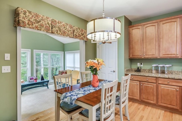 dining room featuring lofted ceiling, a notable chandelier, and light wood-type flooring