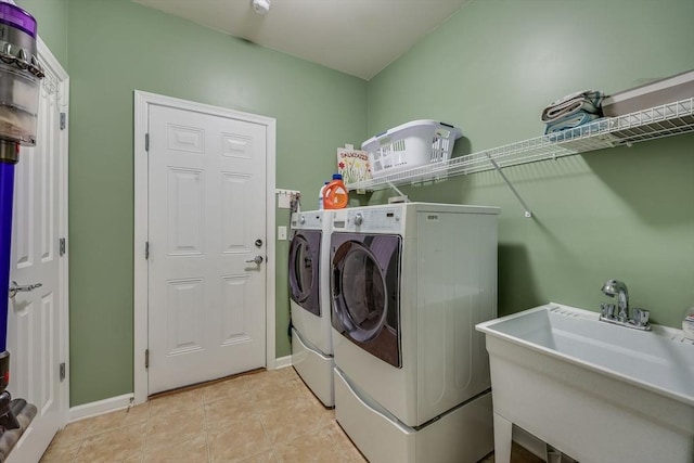 clothes washing area with light tile patterned floors, washing machine and dryer, and sink