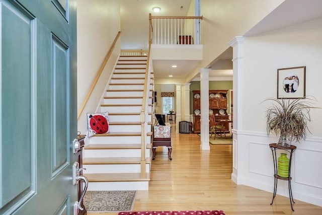 entrance foyer with wood-type flooring, a high ceiling, and ornate columns