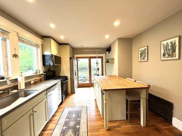 kitchen with light wood finished floors, a sink, a kitchen bar, wood counters, and stainless steel appliances