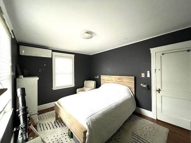 bedroom with baseboards, a wall mounted AC, and wood finished floors