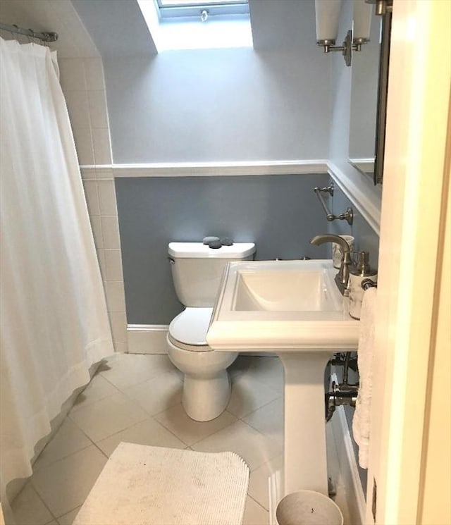 bathroom featuring curtained shower, tile patterned flooring, toilet, and a skylight