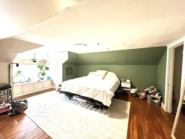 bedroom featuring wood finished floors, vaulted ceiling, and baseboards