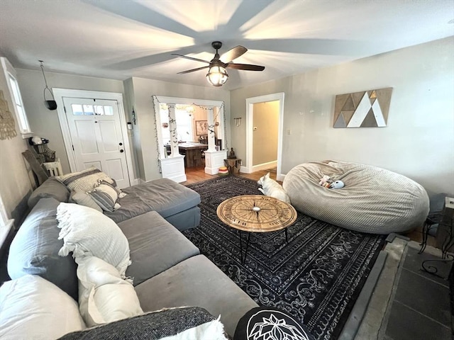 living area with baseboards and ceiling fan