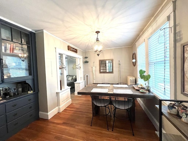 dining space featuring a notable chandelier, crown molding, wood finished floors, and radiator heating unit