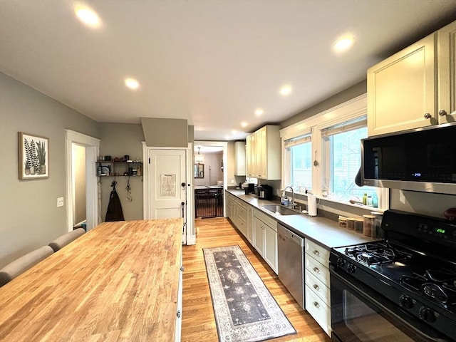 kitchen featuring light wood finished floors, wooden counters, stainless steel appliances, and a sink