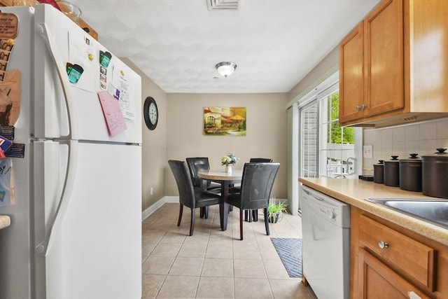 5239 N Main St Unit 7, Fall River, MA 02720 - kitchen with white appliances, brown cabinetry, light tile patterned floors, tasteful backsplash, and light countertops