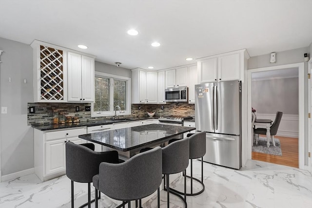 kitchen with marble finish floor, stainless steel appliances, a kitchen bar, and a sink