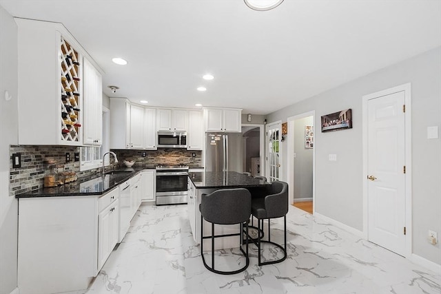 kitchen with a breakfast bar, decorative backsplash, white cabinets, marble finish floor, and stainless steel appliances