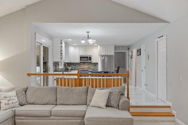 living area featuring baseboards, lofted ceiling, marble finish floor, and an inviting chandelier