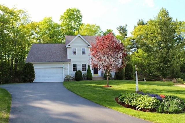 colonial-style house featuring an attached garage, driveway, and a front yard