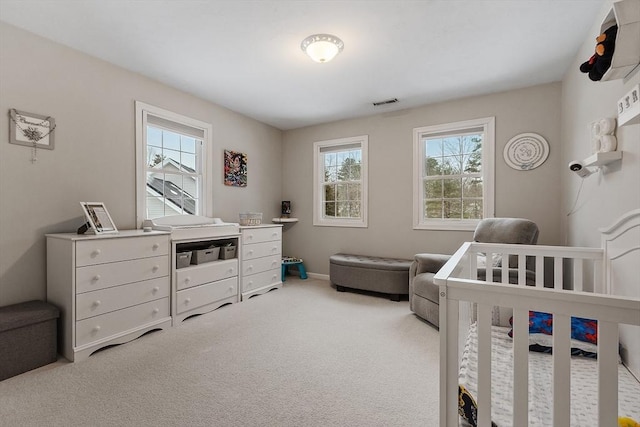 carpeted bedroom with visible vents and a nursery area