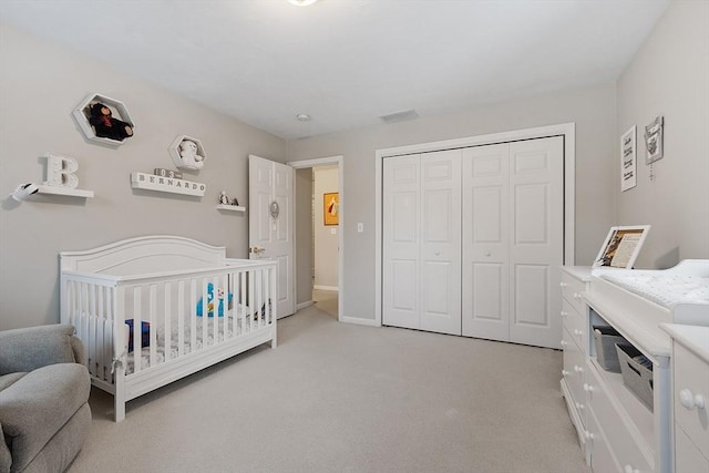 bedroom with a crib, light colored carpet, a closet, and baseboards