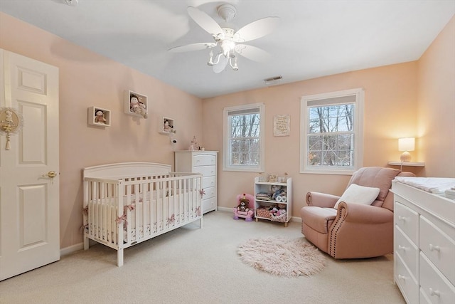 bedroom with visible vents, baseboards, a nursery area, and carpet floors