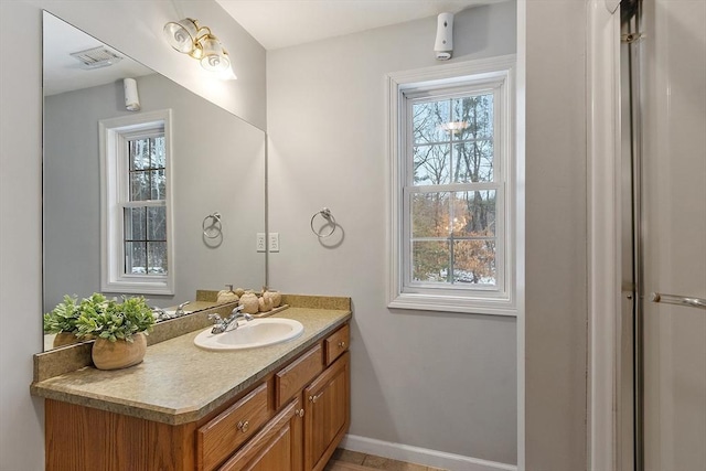 bathroom with vanity, baseboards, visible vents, and a wealth of natural light