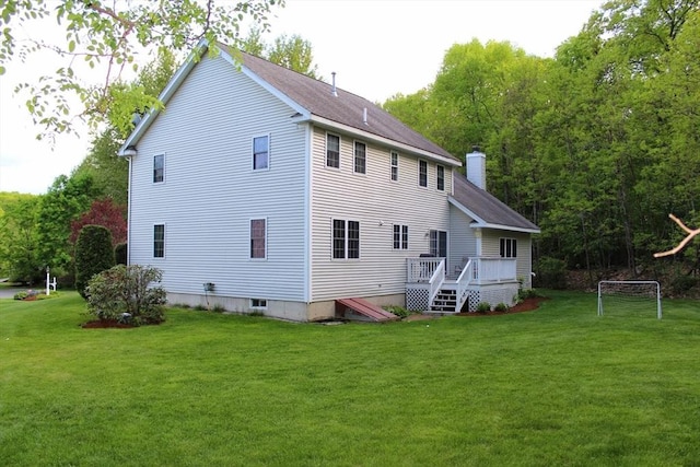 rear view of house featuring a lawn, a deck, and a chimney