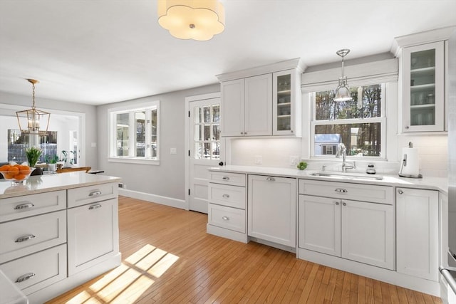 kitchen featuring glass insert cabinets, light countertops, a sink, and white cabinetry