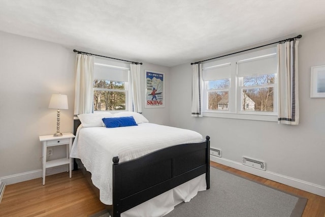 bedroom featuring visible vents, baseboards, and wood finished floors