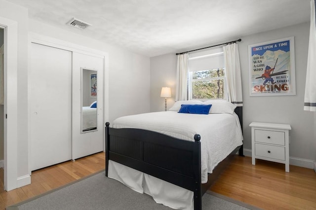 bedroom featuring a closet, wood finished floors, visible vents, and baseboards