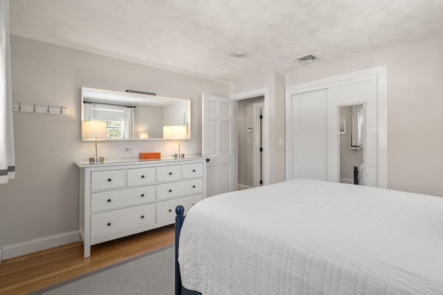 bedroom with light wood-style floors, visible vents, and baseboards