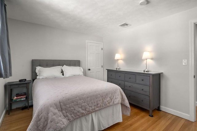 bedroom featuring light wood-style flooring, visible vents, and baseboards