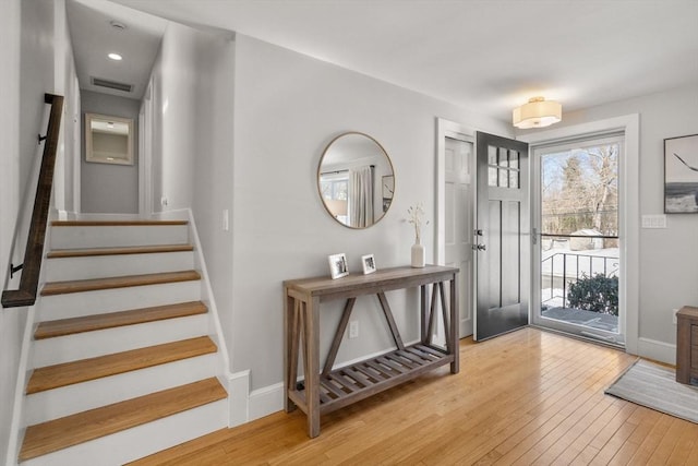 entrance foyer with light wood-style flooring, stairs, visible vents, and baseboards